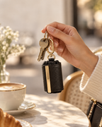 Mauvron Key-Bag gefaltet am Schlüsselbund in der Hand, Café-Tisch im Hintergrund